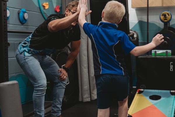 Quad Care exercise physiologist in the quad care gym giving a kid a high five