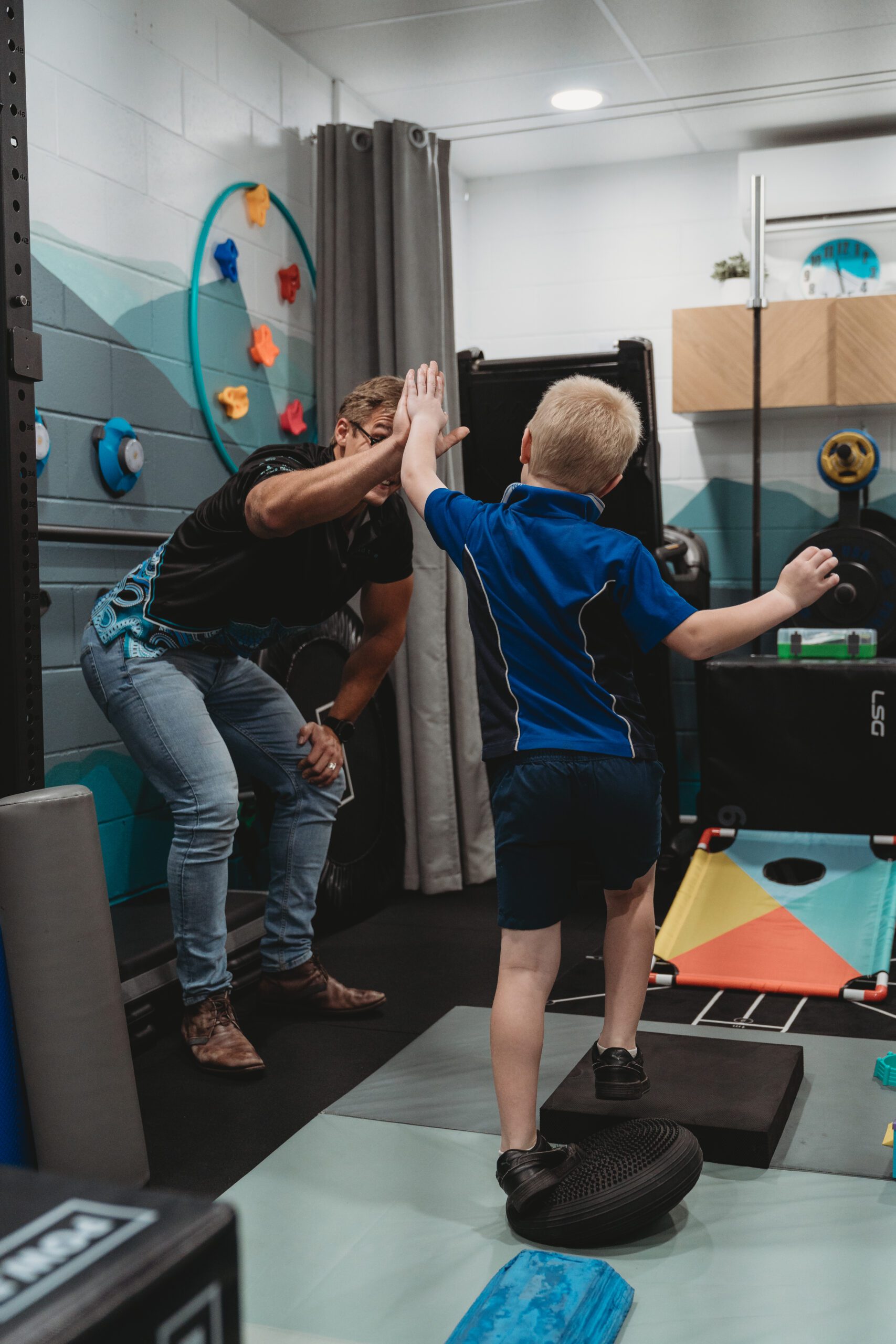 Quad Care exercise physiologist in the quad care gym giving a kid a high five